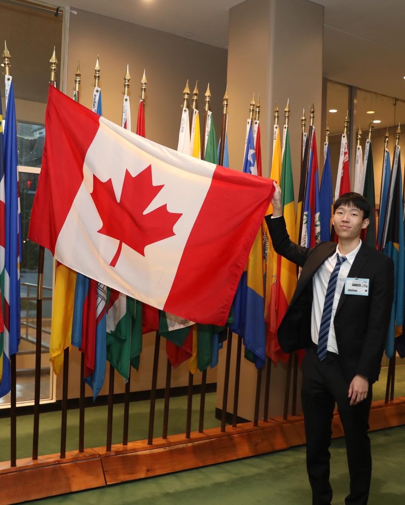 Man in a suit holding up a Canadian flag. 