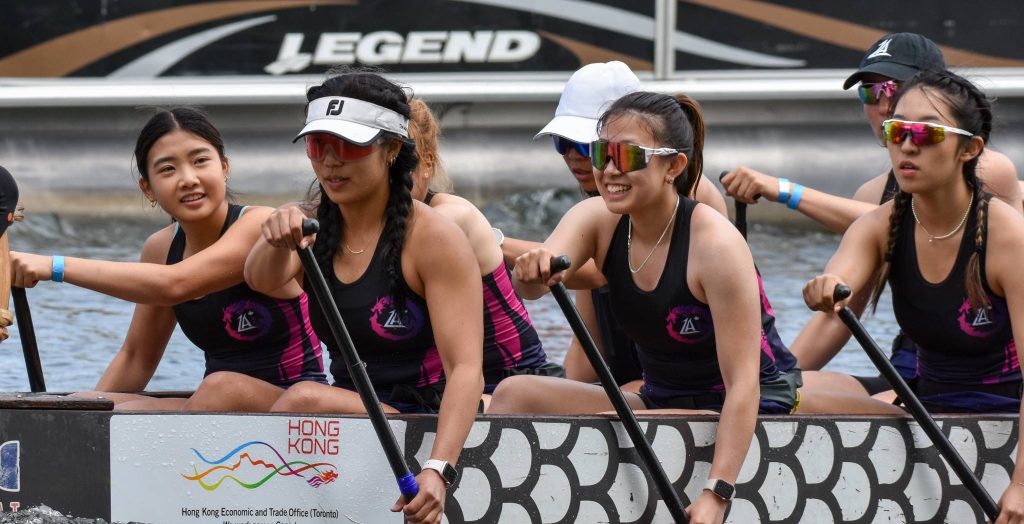 Close up of members of a dragon boat team on paddling on the boat.